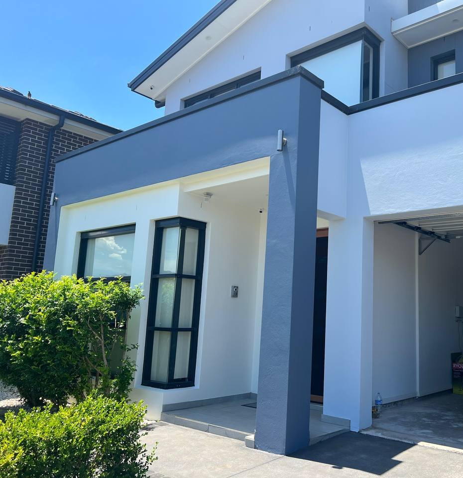 Freshly repainted two-storey rendered home with charcoal feature columns and black window frames